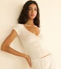 Woman wearing a white tee against a plain background