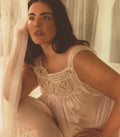 Woman wearing a lace-trimmed dress sitting in a softly lit room.