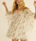 Woman wearing a white floral dress against a plain background